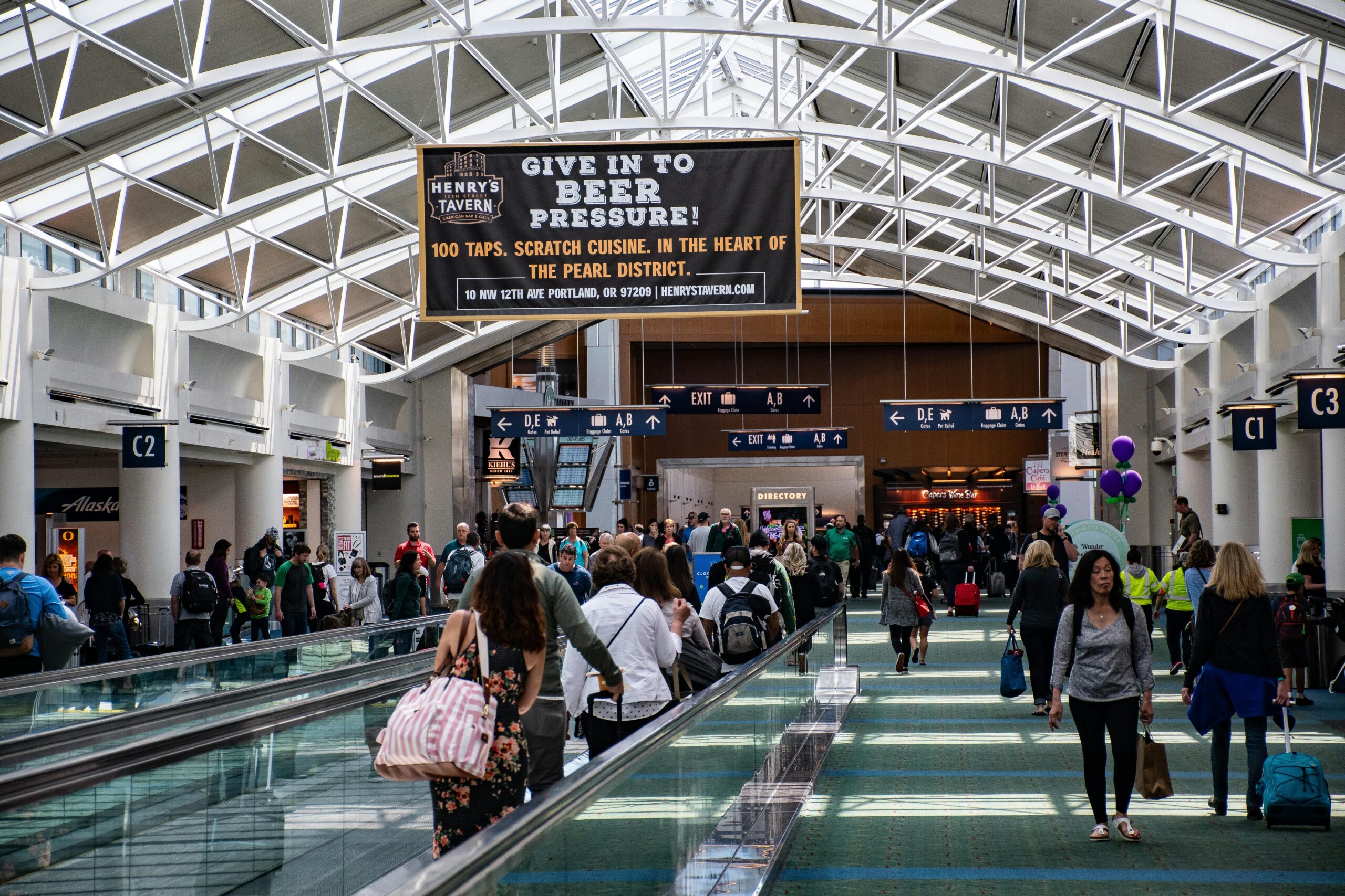 Crowds of people walking through a modern airport terminal, vibrant travel atmosphere.