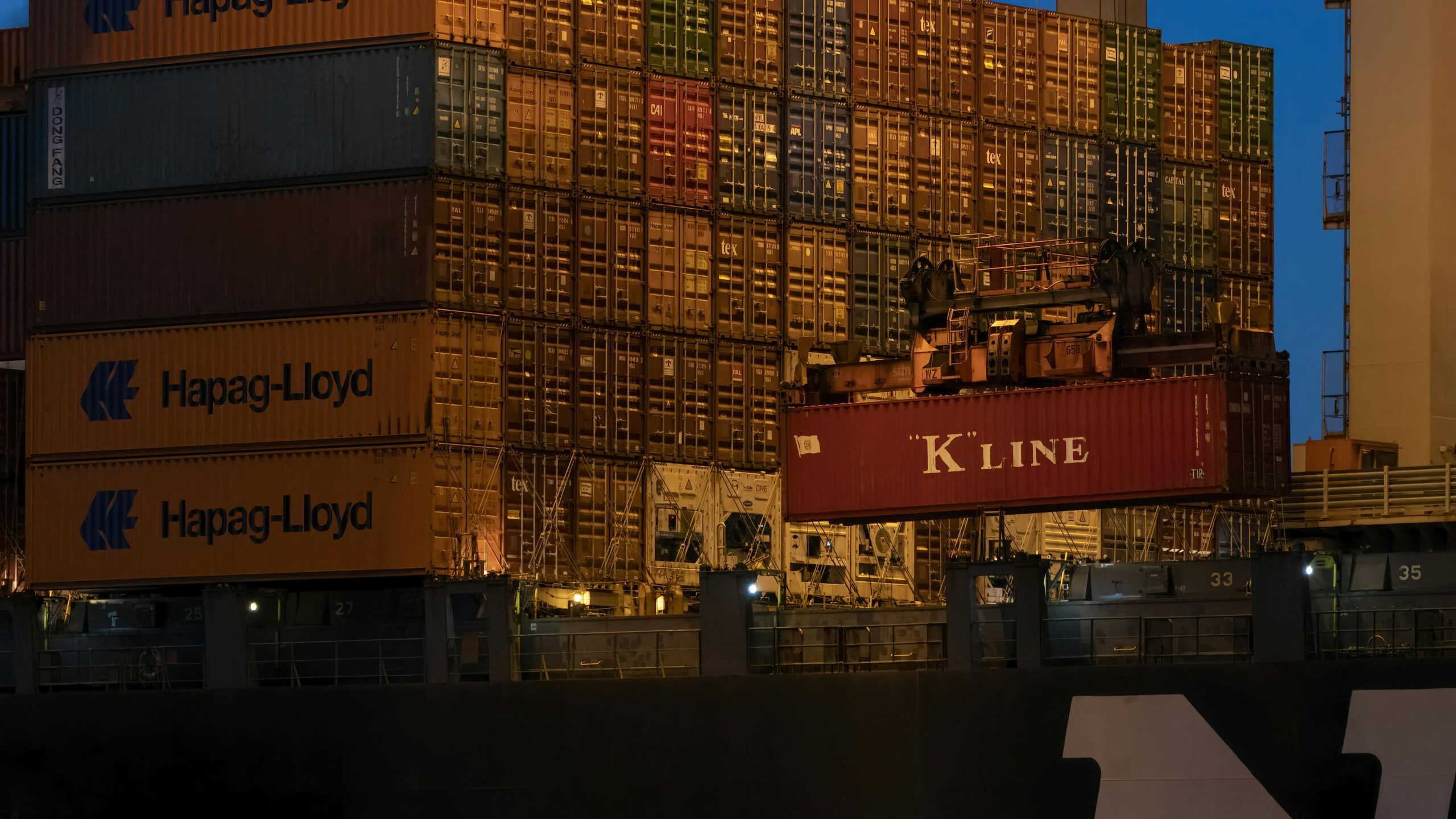 Close-up of stacked shipping containers at Rotterdam port during twilight.